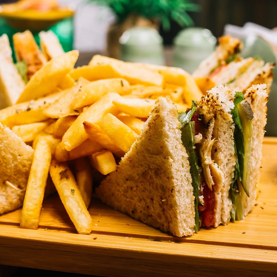 Club sandwiches with chicken, lettuce, and tomato, served with a side of golden french fries.